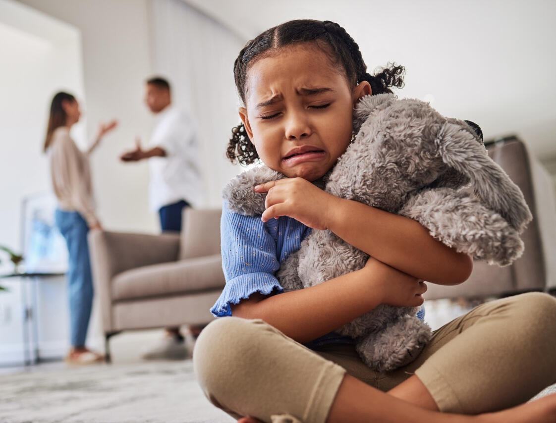 Family Law Investigation to Safeguard Children in Custody Cases An emotionally distressed young girl seeking comfort from her stuffed animal while her parents argue in the background, highlighting how West Coast Private Investigators helps protect children's safety and well-being through compassionate family law invest