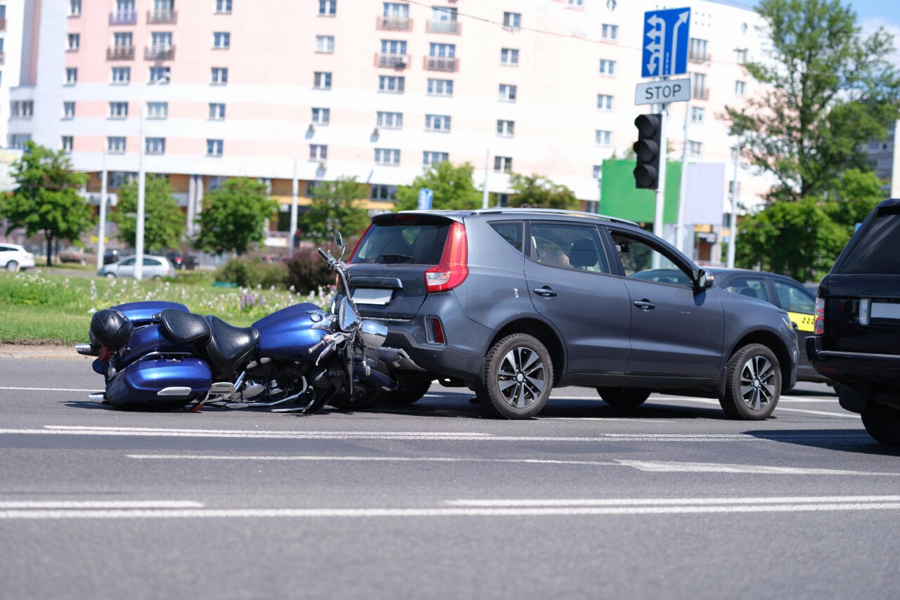 Motor Vehicle Accident Scene for Civil Liability Case in California A toppled blue motorcycle wedged under the rear of a gray SUV at a California intersection following a collision, showcasing the type of accident scenes investigated by West Coast Private Investigators to gather court-admissible evidence in Rancho Santa Ma